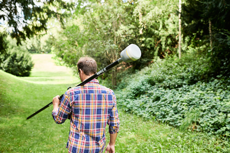 Trimble R12 Man in a park setting with a survey pole and receiver slung over his shoulder