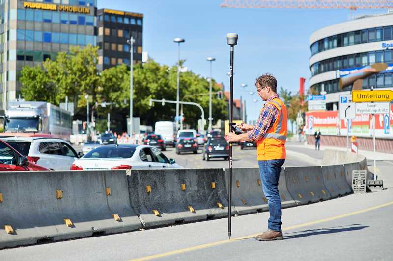 Trimble R12 Man standing in a city street surveying with a GNSS rover unit